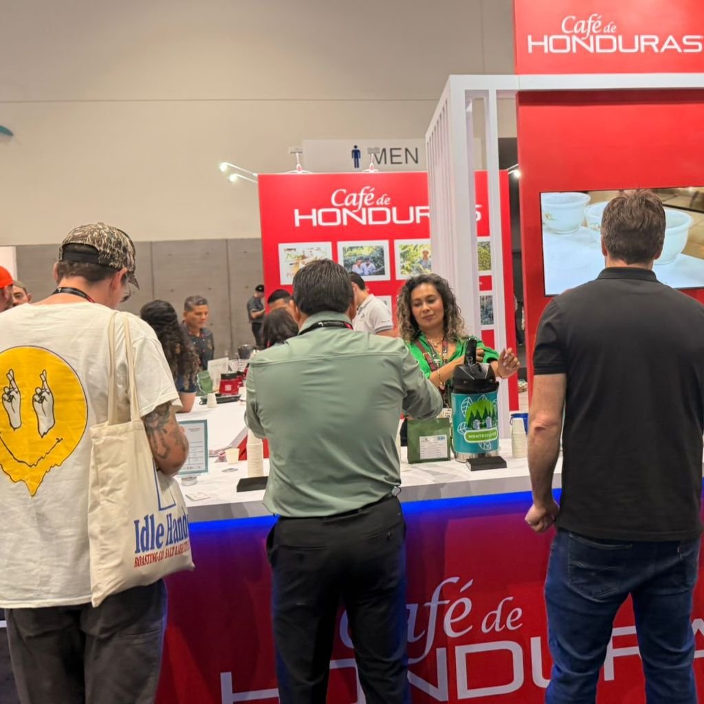 Visitantes internacionales disfrutando las variedades hondureñas como Catuai, Lempira y Parainema en el stand de Café de Honduras, uno de los más concurridos del evento.