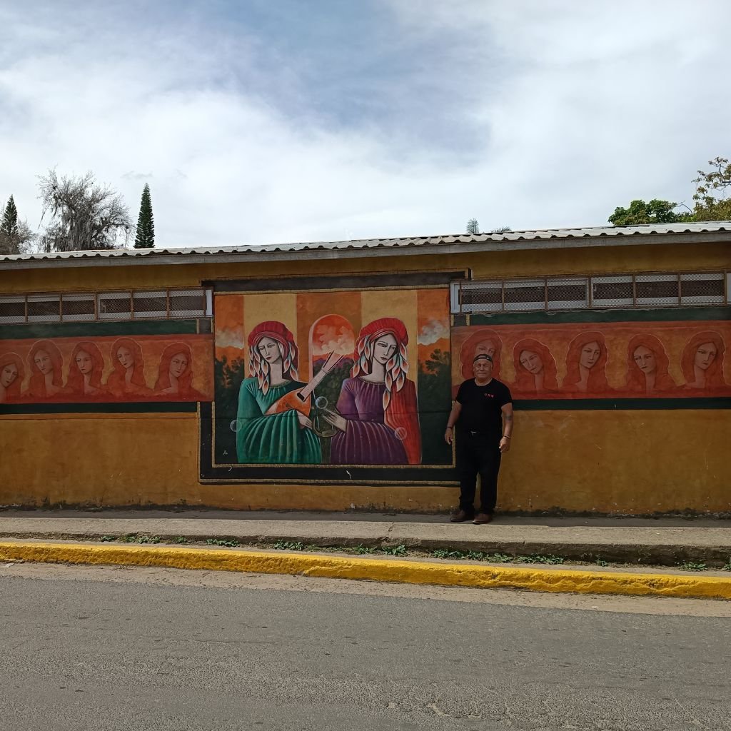 César Milla frente al imponente mural de rostros femeninos que pintó en el centro de Valle de Ángeles, una de sus obras más visibles en el municipio turístico.