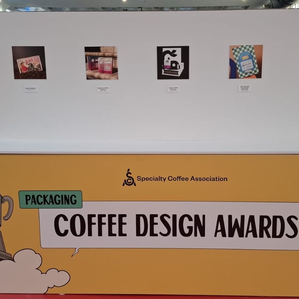 Panel expositivo de los Coffee Design Awards / Categoría Packaging. World of Coffee Brussels 2026. A la derecha, el empaque de The Golden Pig (Honduras).